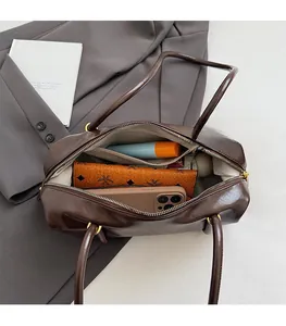 Deep brown Boston bag showing large interior capacity with phone and wallet inside
