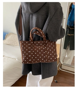 Close-up of a brown polka dot tote bag with handles and adjustable shoulder strap detail