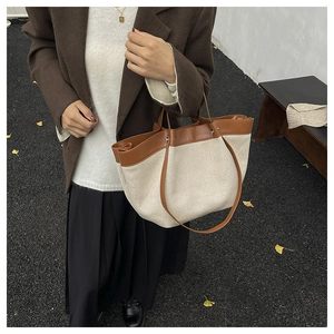 Close-up of canvas and brown leather tote bag styled with autumn blazer and pleated skirt