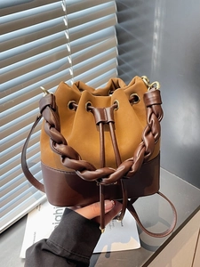 Women's two-tone bucket bag with woven handle and drawstring closure in earth tones