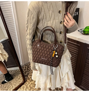 Brown pleated bucket bag detail showing bead tassel and adjustable shoulder strap