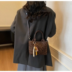 Détail du petit sac bandoulière léopard avec poignées en cuir marron et perles en bois