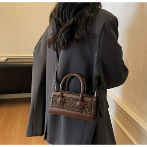 Détail du sac léopard avec poignées rondes porté sur une veste de blazer grise