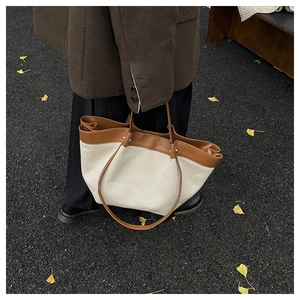 Close-up of canvas and brown leather stitching on a large vintage tote bag