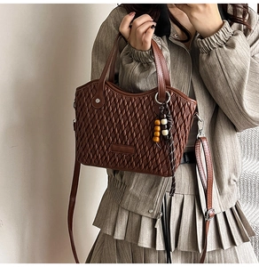 Detailed close-up of brown bucket bag showing woven texture and decorative wooden beads