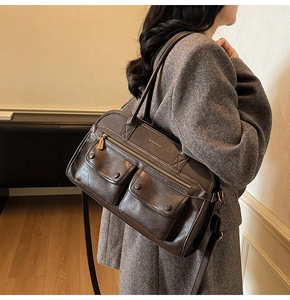 Detail of dark brown leather tote with front flap pockets and gold hardware