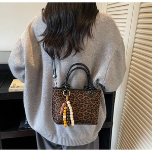 Détail du sac à main léopard avec pompon en perles et poignée en cuir noir