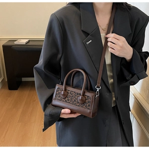 Détail du sac bandoulière léopard vintage avec poignée et sangle en cuir marron