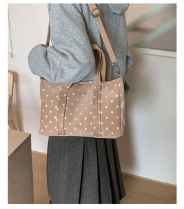 Polka dot tote bag styled as a crossbody on a model with adjustable strap detail