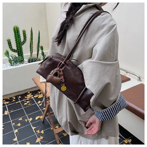 Dark brown leather Boston bag with heart and smiley charms shown as a crossbody detail