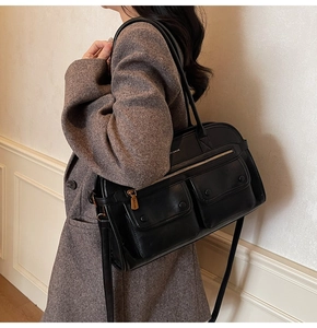 Detail view of black faux leather tote with multiple pockets and adjustable shoulder strap