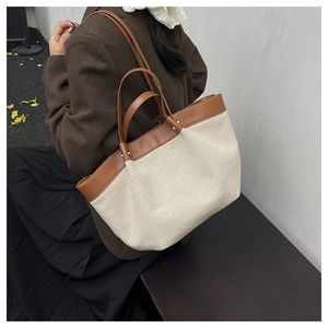 Close-up of canvas and brown leather tote bag with silver studs in autumn outdoor setting