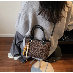 Détail du sac léopard avec breloque en perles de bois et bandoulière réglable chic