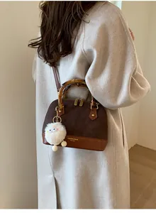 Detail of vintage patchwork handbag with bamboo handle and plush charm on coat