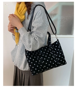 Polished black tote bag with white polka dots featuring detachable shoulder strap detail