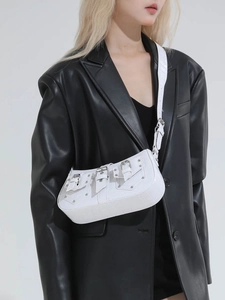 White vintage-style rivet crossbody bag with crocodile texture on a leather blazer