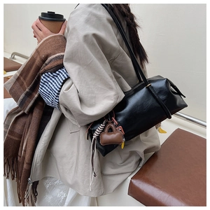 Detail of glossy black Boston bag with decorative charms and premium leather texture