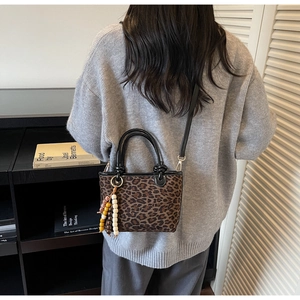 Détail du sac léopard avec pampille en perles et bandoulière noire amovible