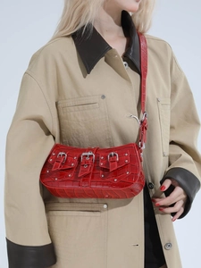 Red crocodile texture shoulder bag with punk rivets and buckles on a stylish model