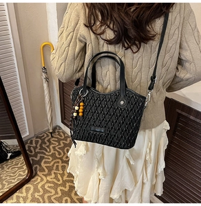 Detail of black woven texture bucket bag with bead charm and adjustable shoulder strap