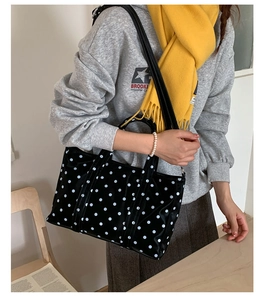 Detailed view of black polka dot tote bag showing adjustable strap and top handles
