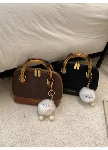 Detail of suede shell bags with vintage bamboo handles and plush charm accessory