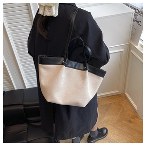 Detail view of large canvas tote bag with black leather straps on model shoulder