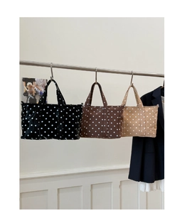 Close-up of three stylish polka dot tote bags in black, brown, and beige colors
