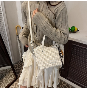 White quilted bucket bag with woven texture and bead pendant shown on a model