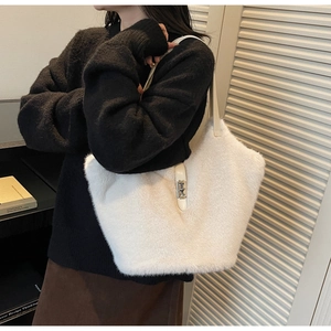 Detailed view of white faux fur tote bag with leather strap worn by a model