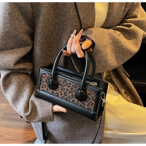 Détail d'un mini sac à main léopard avec finitions en cuir noir et poignées rondes