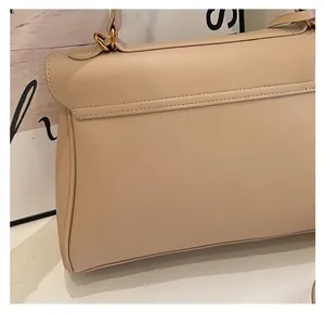 Detailed macro view showing beige leather texture and gold hardware on tote bag