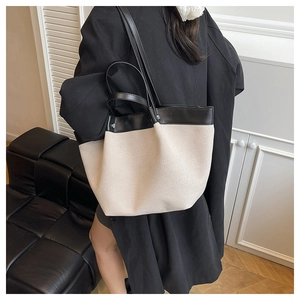 Detail view of large canvas and leather patchwork tote bag styled in a home setting