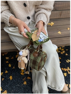 Detail of plaid wool boston bag with leather handles and a cute teddy bear charm