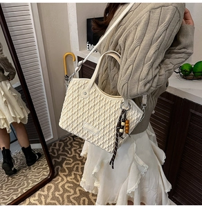 Close-up of cream woven bucket bag featuring quilted texture and vintage wooden bead charm