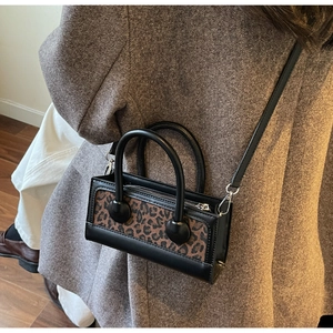 Détail d'un mini sac bandoulière à motif léopard porté par un mannequin en blazer