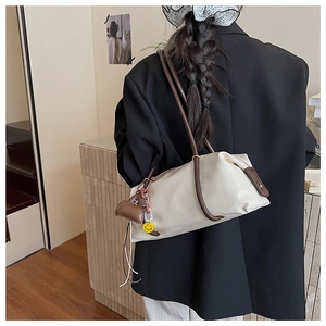 Detail of creamy white faux leather Boston bag with thin brown strap and smiley charm
