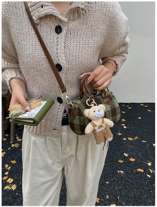 Detail of mini plaid Boston bag with leather handles and a plush bear pendant accessory