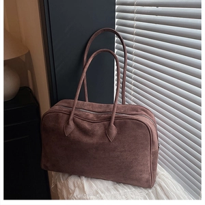 Close-up of brown suede Boston bag with metal zipper on a soft white texture