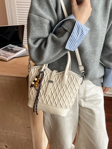 Creamy white quilted tote bag with wooden bead charm and adjustable crossbody strap