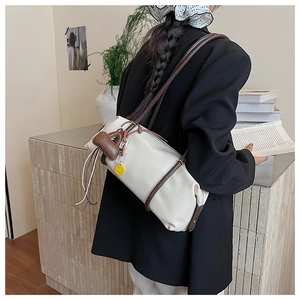 White cylinder shoulder bag with brown leather straps and charms shown on model