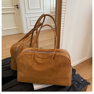 Detail shot of caramel suede tote bag featuring a silver zipper and long shoulder straps