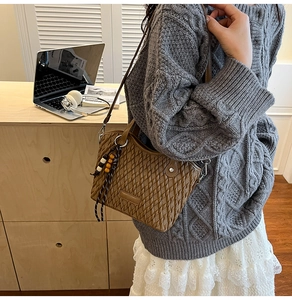 Close-up of brown woven texture bucket bag with beaded tassel detail and slim leather strap