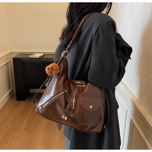 Deep brown glossy tote bag with stylish zipper pockets and a cute plush bear pendant