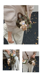 Detail of checkered Boston bag with leather handles and cute bear charm in autumn setting