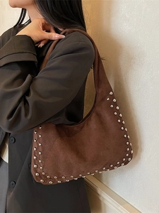 Retro brown suede hobo bag with silver studs worn by a model in a minimalist setting