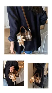 Detail of a brown plaid mini Boston bag featuring a cute teddy bear charm and strap
