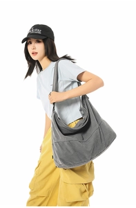 Grand sac bandoulière en toile gris délavé porté par mannequin montrant le drapé et le volume