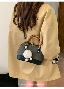 Detail of vintage shell bag with bamboo handle, contrast tones and plush charm decoration