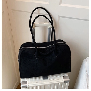 Macro detail of black suede Boston bag with long straps and zipper on a suitcase